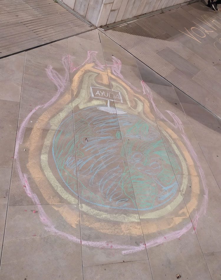 Pintada con tiza sobre acera, el mundo ardiendo, arriba un cartel en el que se lee "Ayuda"